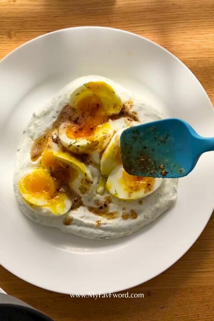 adding butter sauce on eggs with yogurt sauce